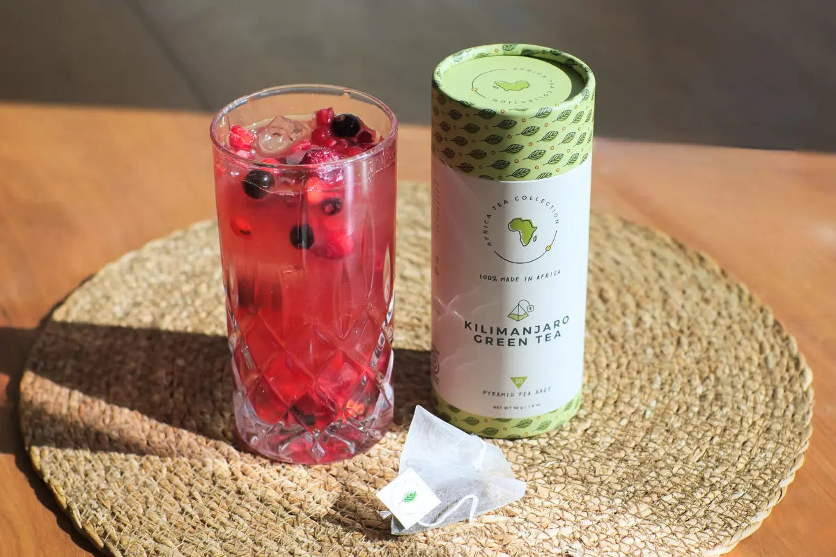 A refreshing mocktail made with Kilimanjaro green tea, mixed with berries and pineapple juice, served with ice cubes in a tall glass, garnished with a slice of lime, set against a vibrant tropical backdrop.