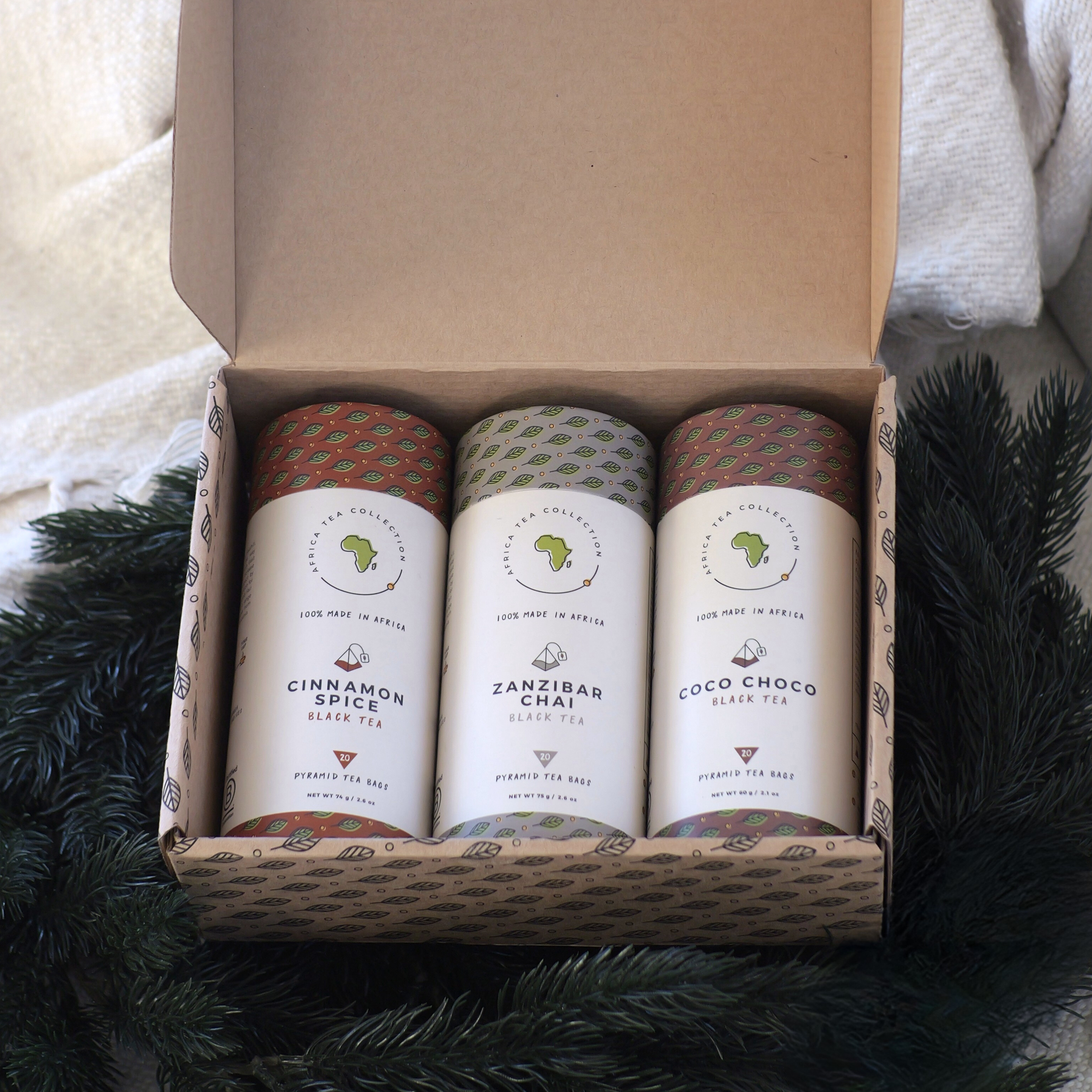 Three tea blends in a cardboard box with decorative elements.