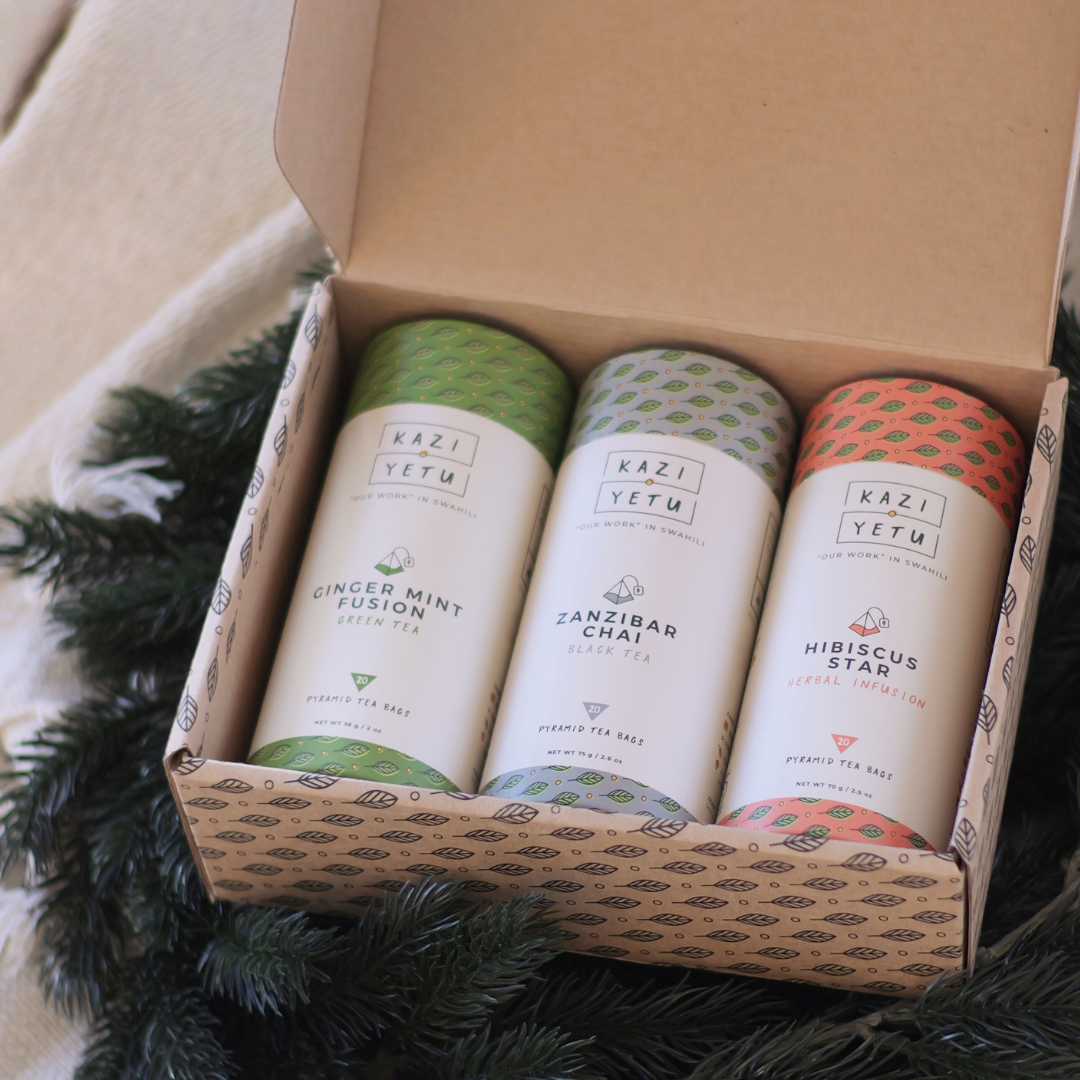Three tea blends in a box with 'Kazi Yetu' branding on a textured surface.