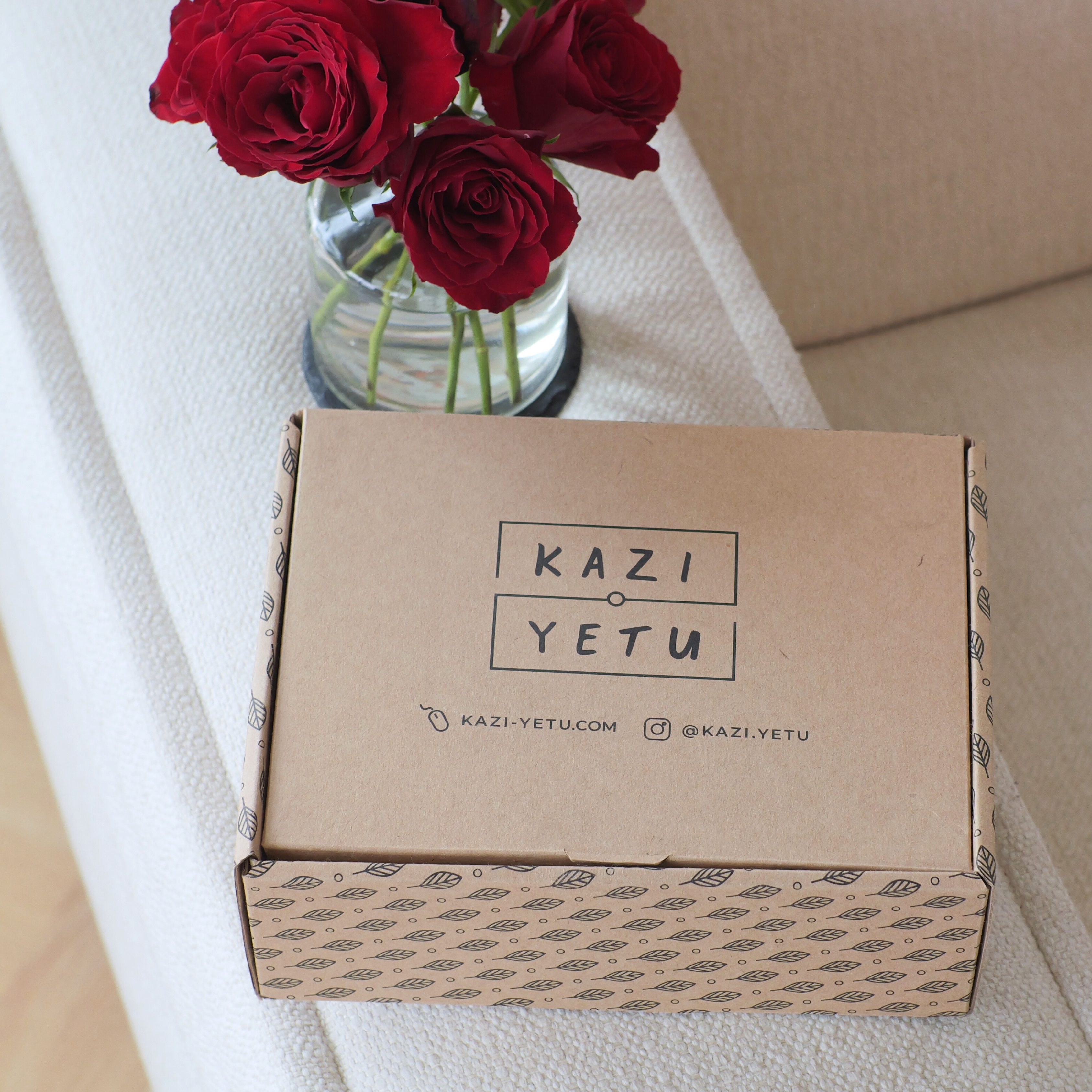 Kazi Yetu box with red roses in a vase on a white surface