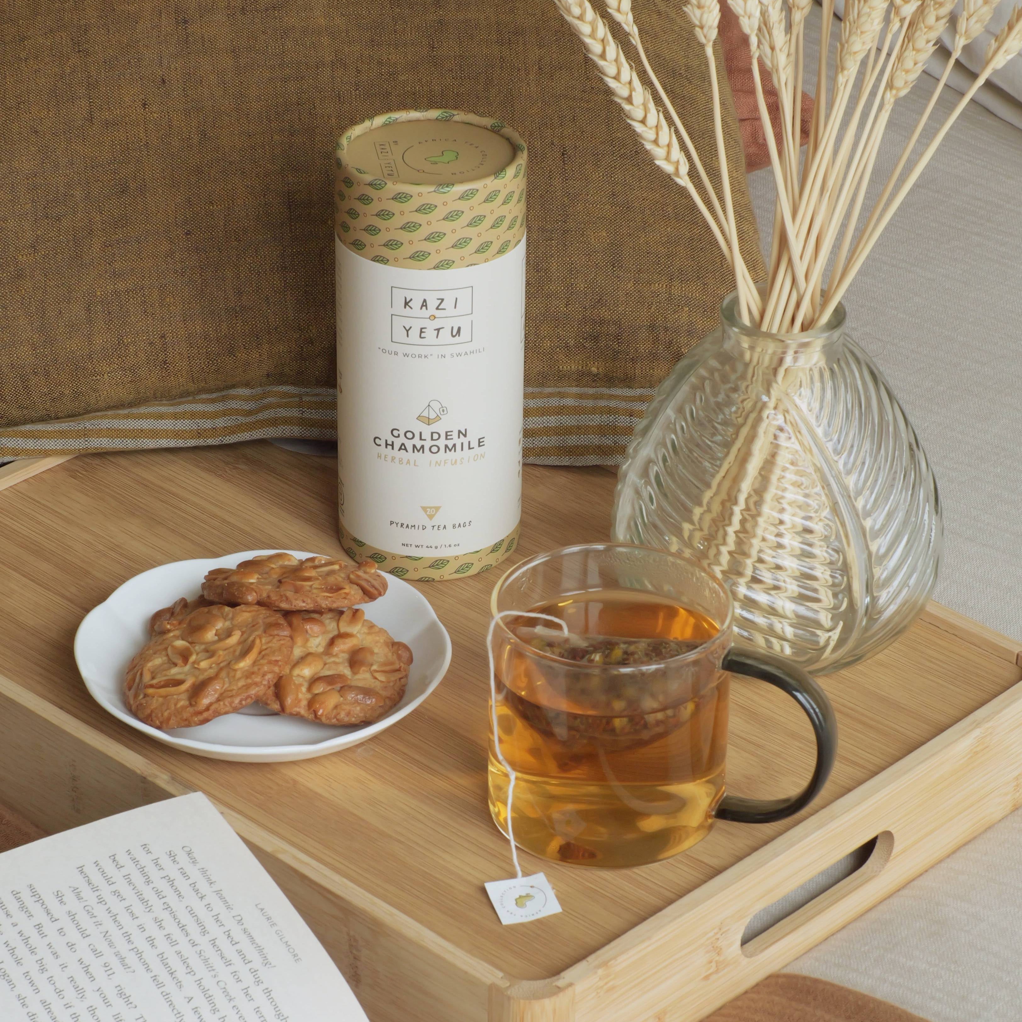 Tray with cookies, Golden Chamomille tea, and a candle on a wooden surface